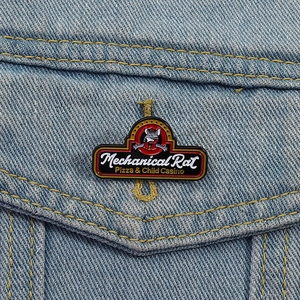 Detailed close-up of a Mechanical Rat enamel pin on a blue denim jacket pocket
