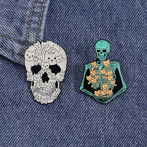 Detailed view of two creative Halloween cat skeleton enamel pins on blue denim fabric