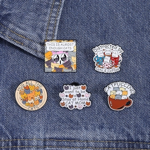 Creative cat enamel pins set featuring catpuccino and kitten pile on denim background