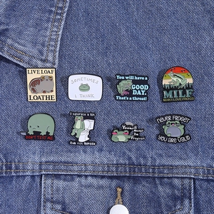 Detail of funny green frog enamel pins pinned on a blue denim jacket pocket