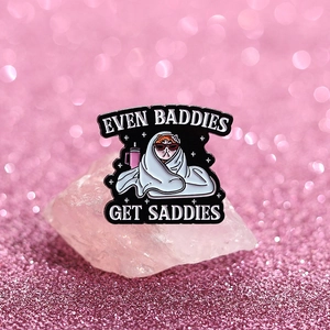 Close-up of enamel cat pin with slogan on pink crystal background for punk fashion decor