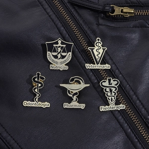 Close-up of golden medical enamel pins with caduceus symbols on black leather jacket