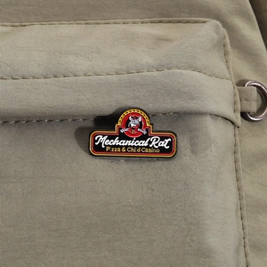 Detail of mechanical rat enamel pin on canvas fabric with red and yellow accents