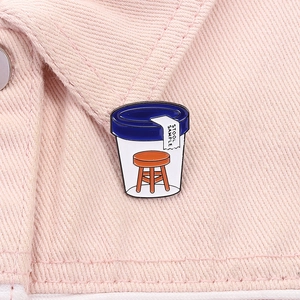 Detail showing the humor Stool Sample enamel pin on pink denim fabric texture