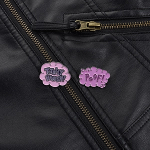 Détail de broches nuage en émail rose avec texte POOF! sur une veste en cuir noir