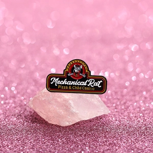 Detailed close-up of a black enamel pin with Mechanical Rat pizza design on pink quartz