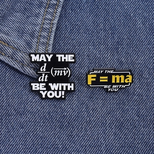 Macro shot of physics pins showing F=ma and derivative formulas on blue denim fabric