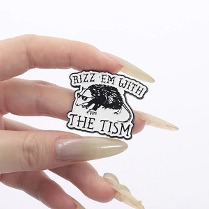 Enamel opossum pin with Rizz Em With The Tism text and sunglasses held by hand