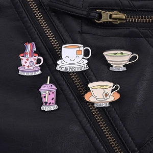 Detail showing five creative tea and coffee cup enamel brooches on a black leather jacket