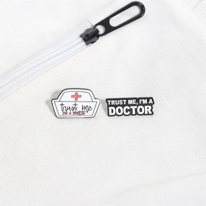 Macro detail of enamel medical nursing brooches with Trust Me text on canvas background