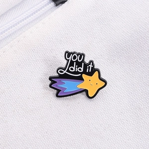 Enamel shooting star pin with You Did It text pinned on a white canvas backpack