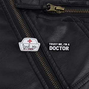 Detail of nurse and doctor enamel pins on a leather jacket lapel with slogans