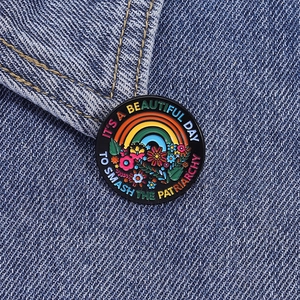 Detail of colorful enamel floral brooch pinned on blue denim jacket with motivational text