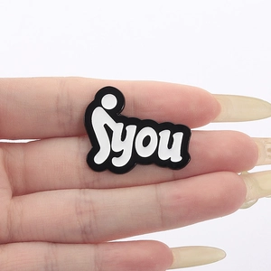 Macro detail of hand holding a creative stick figure enamel pin with YOU lettering