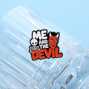 Detail of red devil skull enamel pin with Me and The Devil text on striped glass