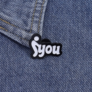 Detail of minimalist stick figure enamel pin with YOU text on blue denim jacket