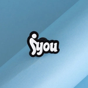 Detailed view of metal enamel pin featuring black and white you text and stick figure design