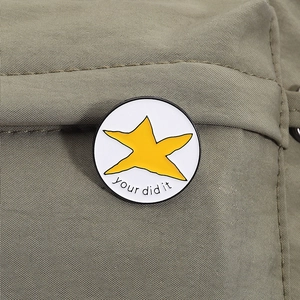 Pin's en émail étoile jaune avec texte sur tissu de couleur vert olive