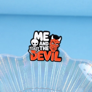 Cartoon enamel pin featuring a red devil and white skull with Me and the Devil text