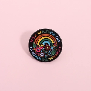 Rainbow and flower enamel pin badge with 'Smash the Patriarchy' slogan on pink background