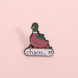 Cute green mallard duck enamel pin with 'chaos' text above a burning city silhouette
