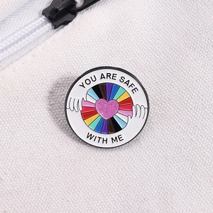 Regenbogen-Emaille-Anstecknadel mit Herz und 'You Are Safe With Me' Text auf weißem Stoff