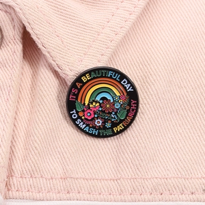 Detailed close-up of a floral enamel pin on pink denim with feminist slogan text