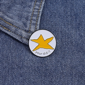 Détail d'un pin's émaillé rond avec étoile sur tissu en denim bleu foncé