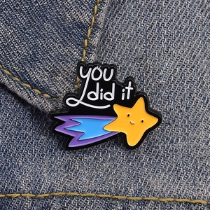 Cute enamel shooting star brooch with 'YOU did it' text on blue denim fabric background