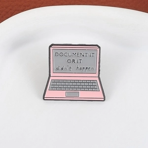 Close-up of pink laptop enamel pin with Document It Or It Didn't Happen quote