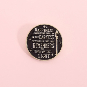 Macro shot of circular enamel lapel pin with gold trim and inspirational quote on black base