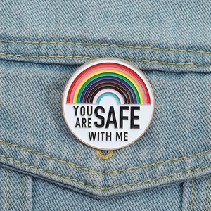 Pin's en émail arc-en-ciel avec slogan de sécurité sur une veste en jean bleue