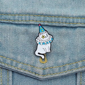 Gros plan d'une jolie broche chat clown blanc en émail sur une veste en jean bleu clair