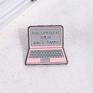 Close-up of pink laptop enamel pin with Document It Or It Didn't Happen quote on canvas