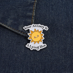 Detalle de pin de sol divertido en tela vaquera con lema motivador sobre ansiedad