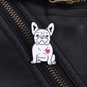Dettaglio di una spilla smaltata bulldog bianco con cuore rosso su pelle nera