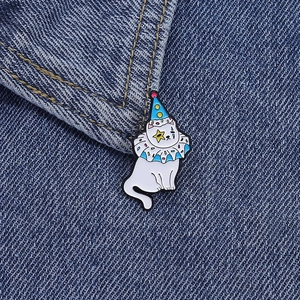 Détail du pin's chat clown blanc avec chapeau à pois bleus sur un tissu en jean
