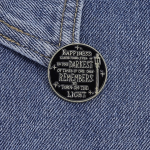 Enamel brooch with inspirational quote on denim fabric background macro view