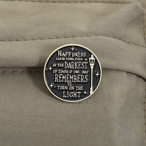 Macro shot of circular enamel lapel pin with gold text on black canvas background