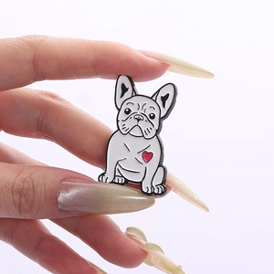 Dettaglio di una spilla smaltata a forma di bulldog bianco con cuore rosso in mano