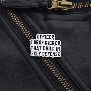 Detail of white enamel cloud pin with humorous quote on a black leather jacket