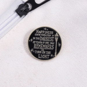 Close-up of a circular enamel pin with a street lamp and quote on white canvas