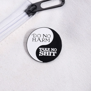 Détail macro du pin's yin yang en émail avec texte sur fond de toile de canevas blanc