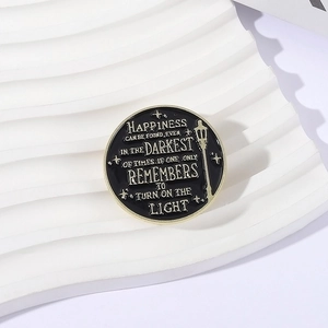 Detail of round enamel pin featuring a lamp post and motivational quote on white stand