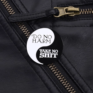 Détail d'un pin's émaillé Tai Chi Yin Yang sur une veste en cuir noir stylée