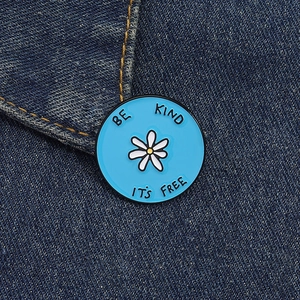 Détail de la broche ronde en émail bleu sarcelle avec marguerite et texte Be Kind
