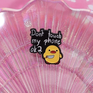 Detailed close-up of a funny duck enamel pin with 'Don't touch my phone ok?' text