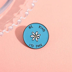 Broche en émail bleu avec marguerite et phrase motivante sur fond rose tendre