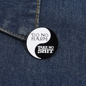 Détail du pin's émaillé Yin Yang avec texte créatif épinglé sur une veste en jean