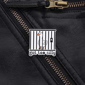 Detail of Silly Goose enamel pin featuring a goose in a cage on a black leather jacket